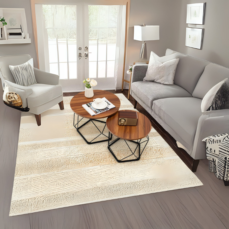 Gray sofa living room from Grella Boutique with round wooden coffee tables, cream rug, and French doors.